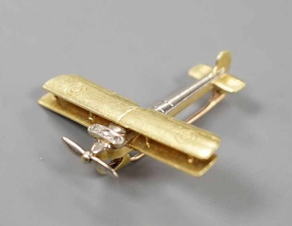 An early 20th century 15ct, white metal and three stone diamond set bi-plane brooch, with revolving propeller, 31mm, gross weight 4.6 grams.
